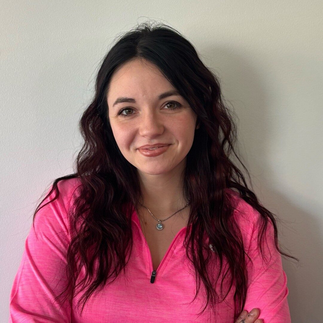 Woman in pink shirt smiling at camera.